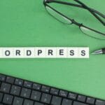 laptop keyboard, glasses and pen with Wordpress alphabet words.