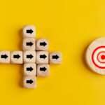 Concept of target marketing. Wooden blocks with arrow and target on blue background. Success concept