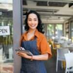 Small business entrepreneur at cafe entrance using digital tablet