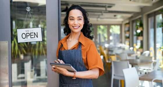 Small business entrepreneur at cafe entrance using digital tablet