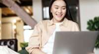 Happy asian woman resting at home with laptop, watching videos or browsing website on computer